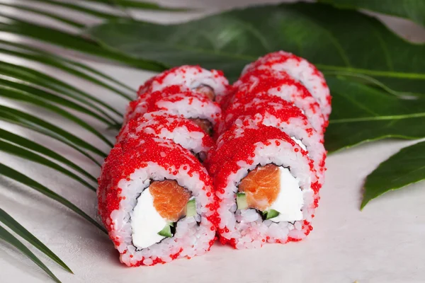 Masago Sushi roll Orange merah Philadelphia keju, salmon, bawang hijau masih hidup di trapicheskih Cunha daun Jepang — Stok Foto