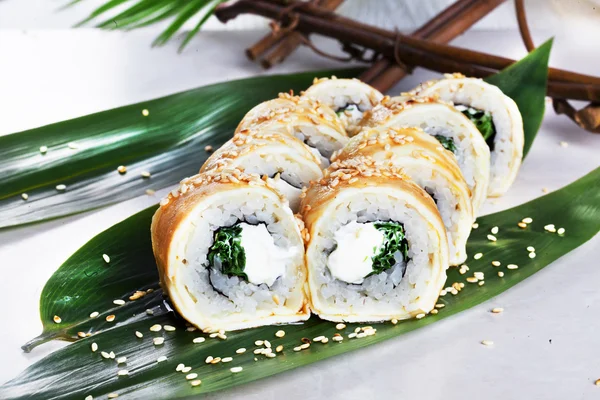 Sushi-Rolle mit Ei-Omelette Philadelphia-Käse und grünen Zwiebeln in einem Stillleben tropischen Blatt japanische Küche — Stockfoto