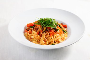 pasta with vegetables, tomatoes, zucchini, peppers, isolated on white background tomato sauce Round plate menu