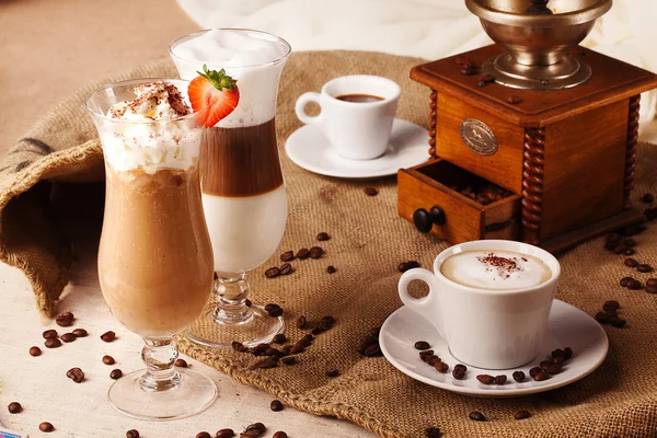 Different types of coffee whipped cream strawberries still life with grinder beans — Stock Photo, Image