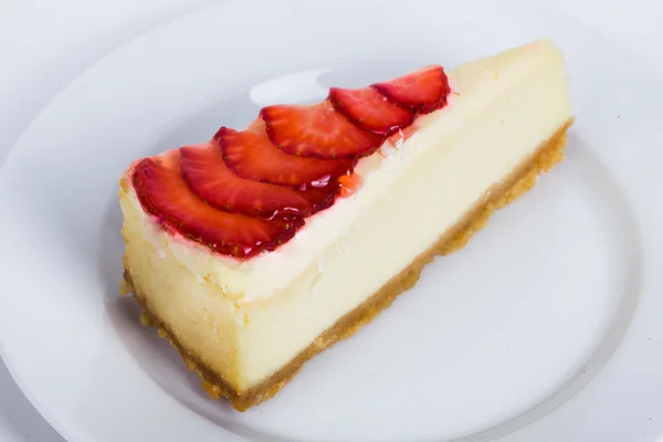 Käsekuchen mit Gelee und Erdbeerscheiben auf einem Teller in Großaufnahme für das Menü — Stockfoto