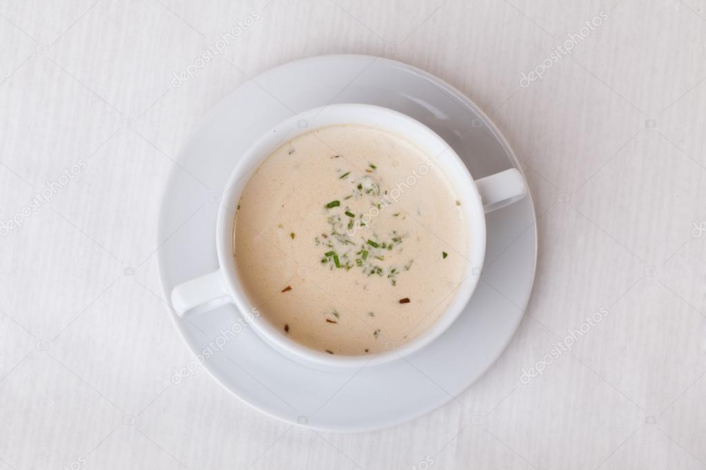 simple white cream soup with herbs in a cup handle on top of the menu isolated