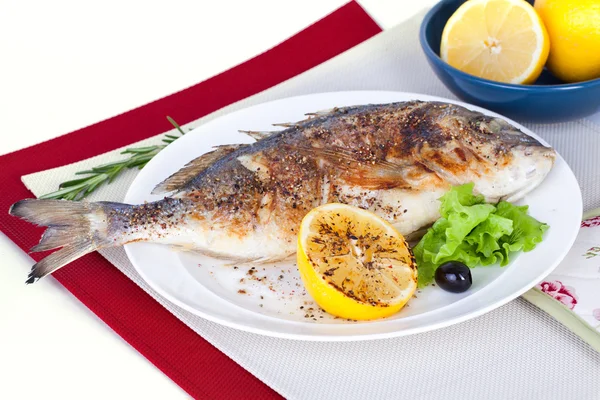 Fish on a plate with lemon and olives in still life — Stock Photo, Image