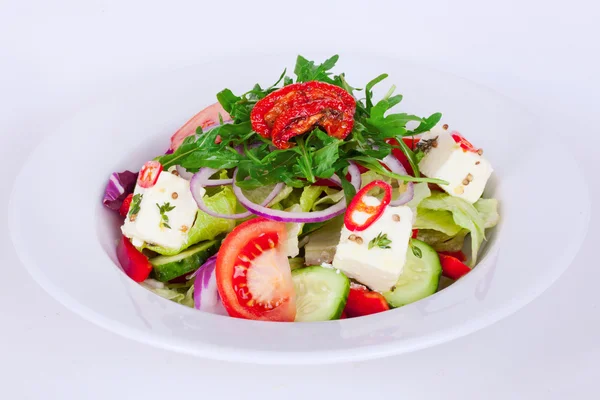 Greek salad cucumber feta thyme, red onion, sun-dried tomatoes  plate isolated white background arugula — Stock Photo, Image