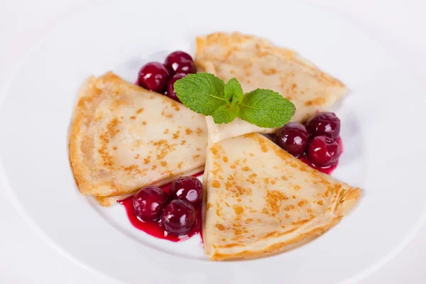 Frittelle con salsa di ciliegie e menta su un piatto isolato — Foto Stock