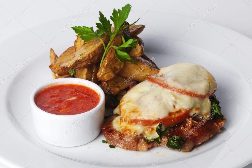 beef, pork, veal, roasted meat with tomatoes and mayonnaise, potato wedges in the peel on a plate isolated white background