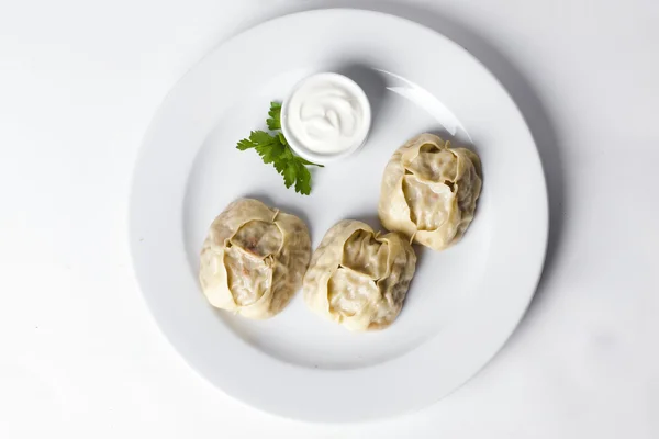 Manti dumplings ravioli stora stora stora med crème fraiche och persilja på en tallrik menyn för restaurang café isolerade vit bakgrund — Stockfoto