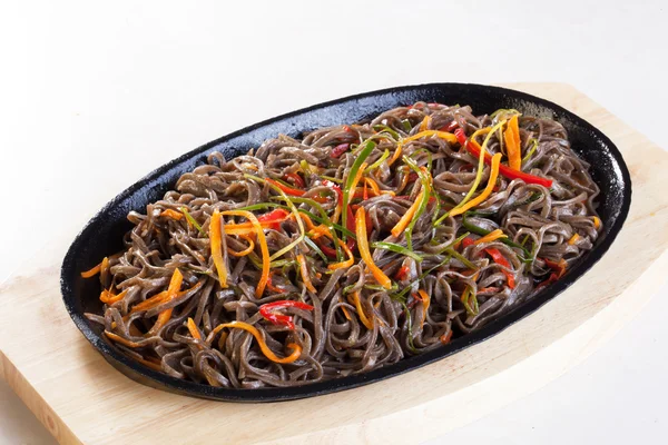 Wok fideos de trigo sarraceno con verduras zanahorias pimienta puerro sartén de hierro fundido en una madera —  Fotos de Stock