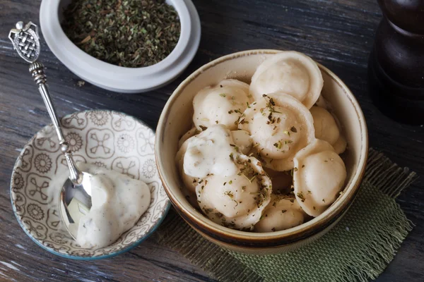 Dumplings, ravioli, tortellini, pelmeni bowl, olijf kruidensaus, Zilveren Lepels, stilleven houten — Stockfoto