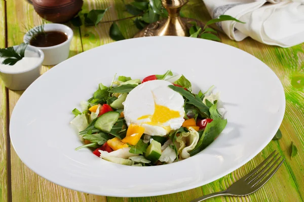 Salada com ovo escalfado, pepinos, arugula, repolho, pimentas, ainda vida em uma mesa de madeira quadro verde comida bonita — Fotografia de Stock