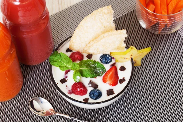 Yogurt with berries and mint strawberry blueberry chocolate crumb still life, carrot sticks, juice bottles — Zdjęcie stockowe