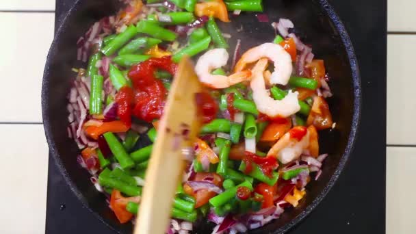 Vegetables frying pan on top, green beans, tomatoes, onions, wood, spatula, stirring  food shrimp — Stock Video