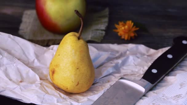 Pear cut with a knife, a wooden table, hands, close-up, still life, retro, black background — Stock Video