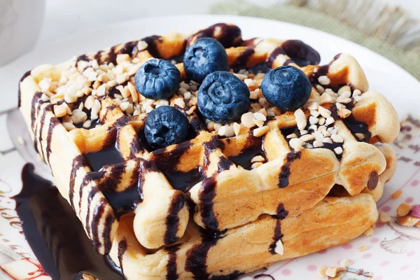 Belgian waffles with peanut chocolate sauce and blueberry, bilberry, whortleberry, huckleberry, hurtleberry, blaeberry on a plate — Stock Photo, Image
