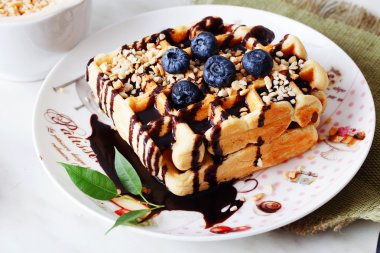 Belçika waffle fıstık çikolata sosu ve yaban mersini, bilberry, whortleberry, huckleberry, hurtleberry, blaeberry bir plaka üzerinde