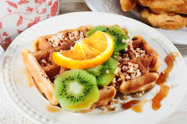 Belgian waffles with orange, kiwi, nuts on a plate close-up — Stock Photo, Image
