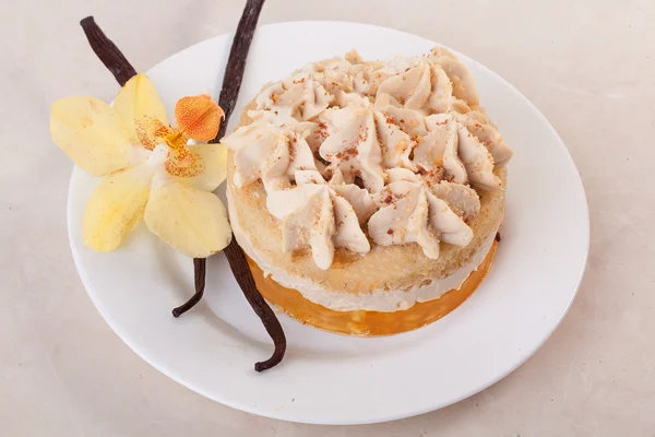 Torta con vaniglia, dessert, bastoncini, fiore, orchidea, su un piatto primo piano, strati di crema — Foto Stock
