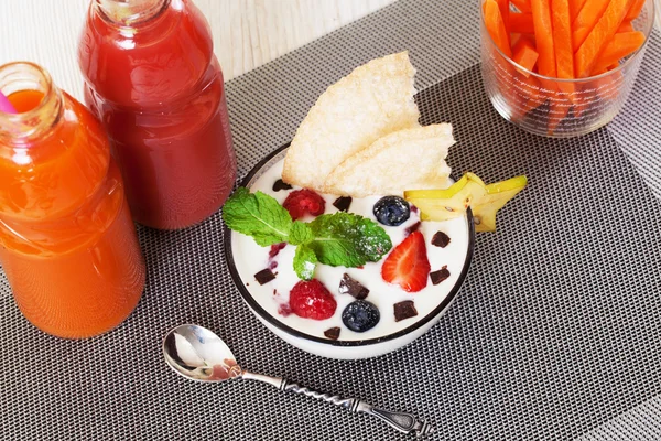 Yogurt with berries and mint strawberry blueberry chocolate crumb still life, carrot sticks, juice bottles — Stock Photo, Image