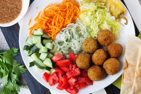 Falafel plaka garnitür için havuç, lahana, soğan, salatalık, domates, Natürmort, yemeğin üstüne — Stok fotoğraf