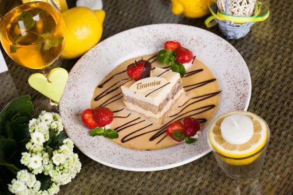 Tiramisu sur une assiette avec des fraises et de la sauce dans la nature morte, design chocolat — Photo