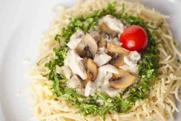 Pasta with mushrooms and cherry tomatoes, lined by a circle of greenery closeup — Stock Photo, Image