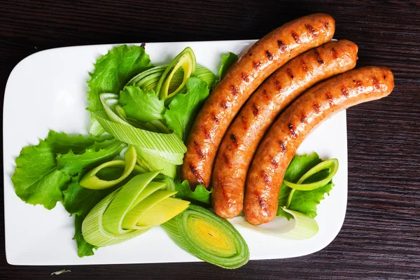 Grilled sausages with easy side dish of leek and lettuce — Stock Photo, Image