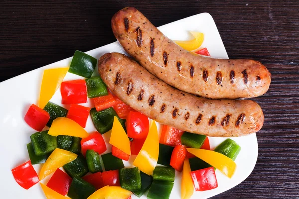 Grilled sausages with easy side dish of peppers, yellow, green, red — Stock Photo, Image