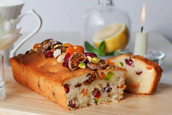 Plum cake food candied fruits, nuts, dried apricots, figs, close-up still life with tea and lemon — Stock Photo, Image