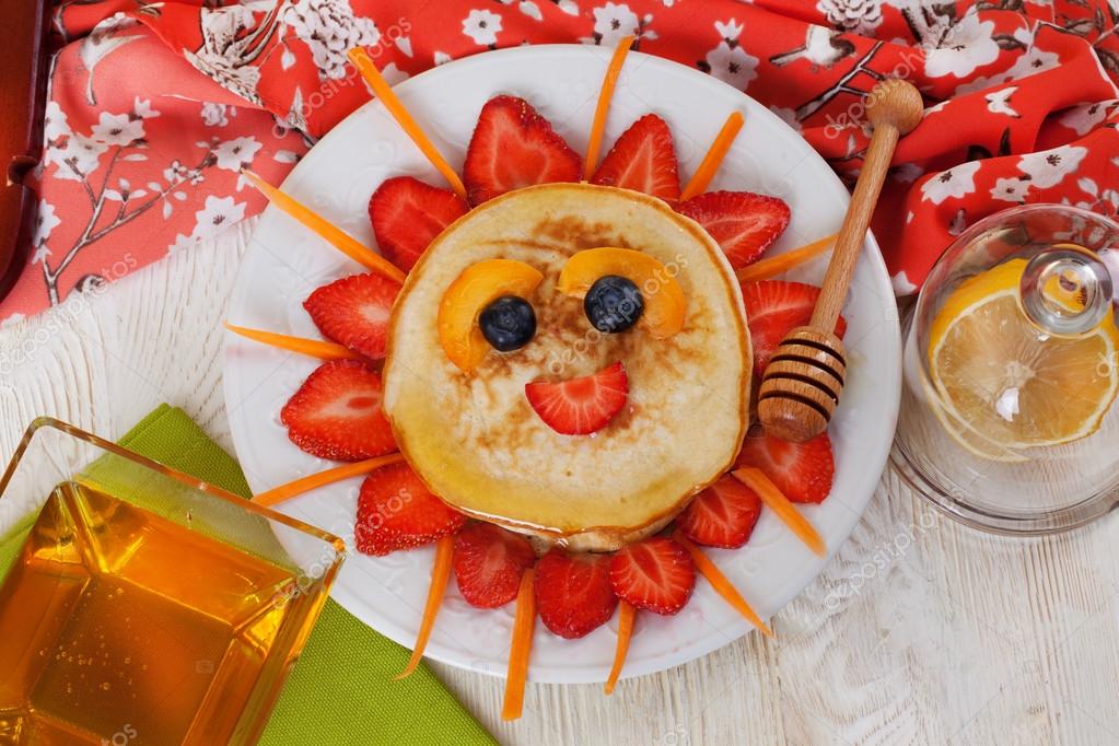 Childrens breakfast pancakes smiling face of the sun strawberry