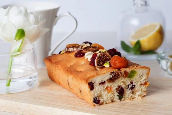 Plum cake food candied fruits, nuts, dried apricots, figs, close-up still life with tea and lemon — Stock Photo, Image