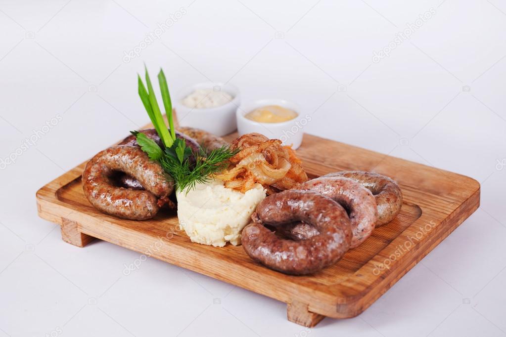 sausages with mashed potatoes, wooden board, isolated, white background, fried green onions, parsley, sauce