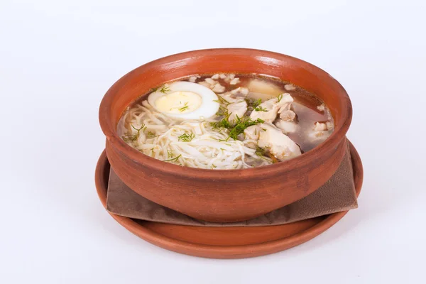 Sopa de frango com arroz, ovo e macarrão em panela de barro marrom isolado em um fundo branco — Fotografia de Stock