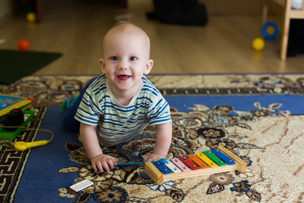 Little boy, baby, xylophone musical instrument, fun rejoices at home, playing on carpet — Stock Photo, Image
