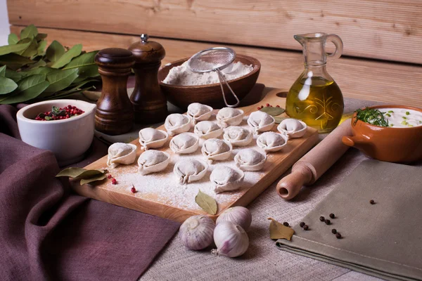 Dumplings rural village board bay leaf still-life plank wood flour ingredients appetizing nourishing hand modeling — Stock fotografie