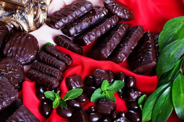 Chocolats et gelées en vrac sur un tissu de soie rouge belle — Photo