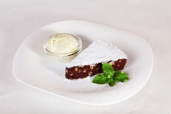 Шоколадный кекс с сахарной пудрой и мятной пластиной на белом фоне — стоковое фото