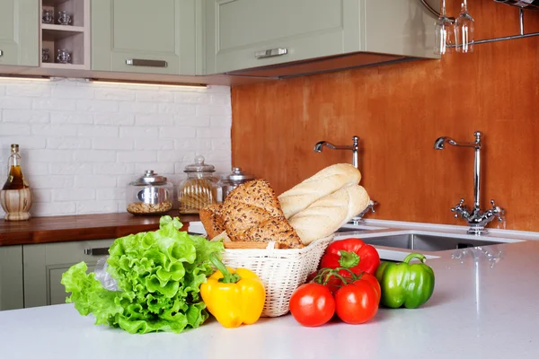 Cozinha projeto luz produtos hortícolas frescos, cesta de pão, alface, pimentas, tomates, compras, duas pias com tabela de massas de banco de torneiras de cozinha — Fotografia de Stock