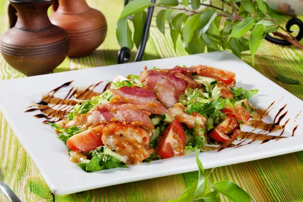 Салат с куриными наггетсами, ругулой, беконом, помидорами, бальзамическим соусом на деревянном столе — стоковое фото