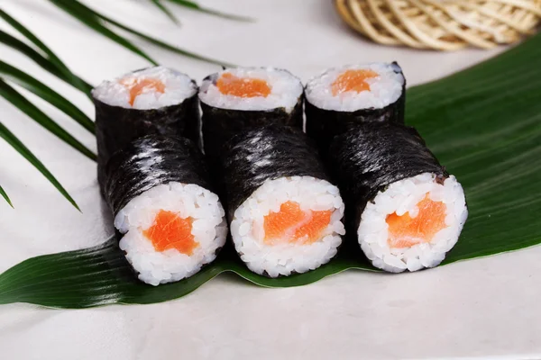 Sushi gulung salmon chives mini kappa maki dalam masih hidup pada daun tropis — Stok Foto