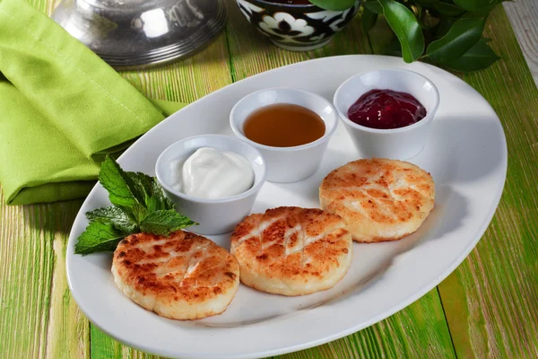 Homemade cheesecakes with sour cream and jam still life wooden table green beautiful board appetizing — Stock Photo, Image