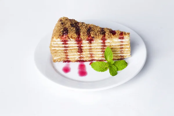 Gâteau gâteau au miel sur une assiette avec sauce à la menthe et aux petits fruits framboise isolé fond blanc — Photo