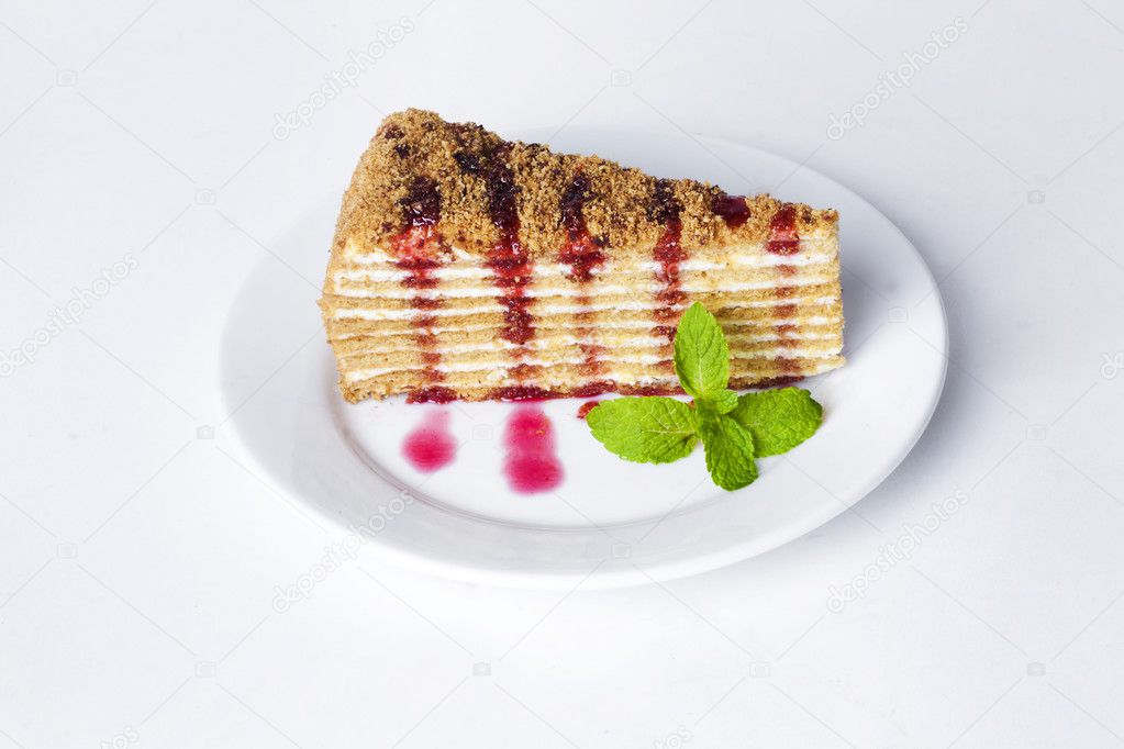 Cake honey cake on a plate with mint and berry fruit raspberry sauce isolated white background