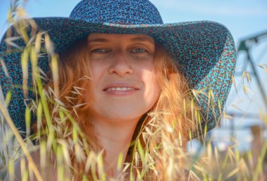 Şapkalı gülümseyen bir kızıl saçlı kız portresi.