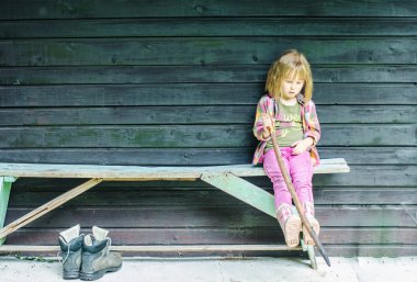 Sopayla bankta oturan küçük Kızıl saçlı kız