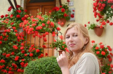 Portrait of red-haired woman in front of red flowers