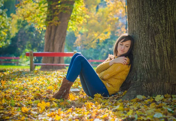 나무 줄기 가까이 앉아서 꿈 예쁜 여자 — 스톡 사진