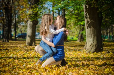 Anne ve kızı sonbahar parkta sarılma