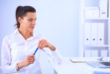 Ofiste dizüstü bilgisayarı olan çekici bir iş kadını.