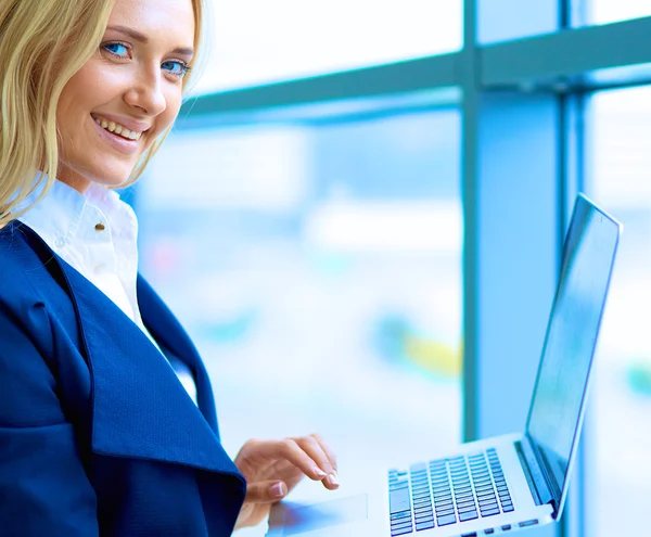 Femme d'affaires debout contre la fenêtre de bureau tenant ordinateur portable — Photo