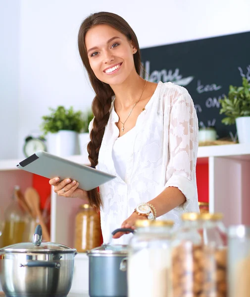 Mujer joven usando una tableta para cocinar en su cocina —  Fotos de Stock